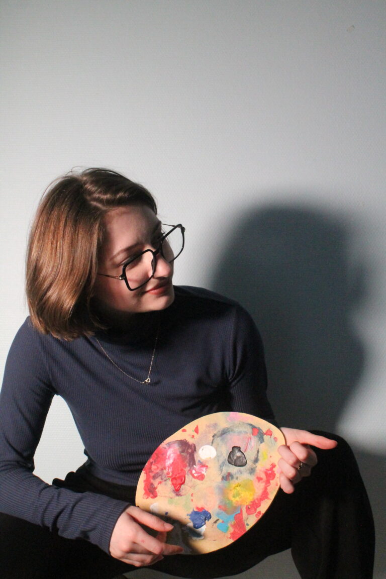 photo d'une fille qui rigole avec une palette de peinture à la main